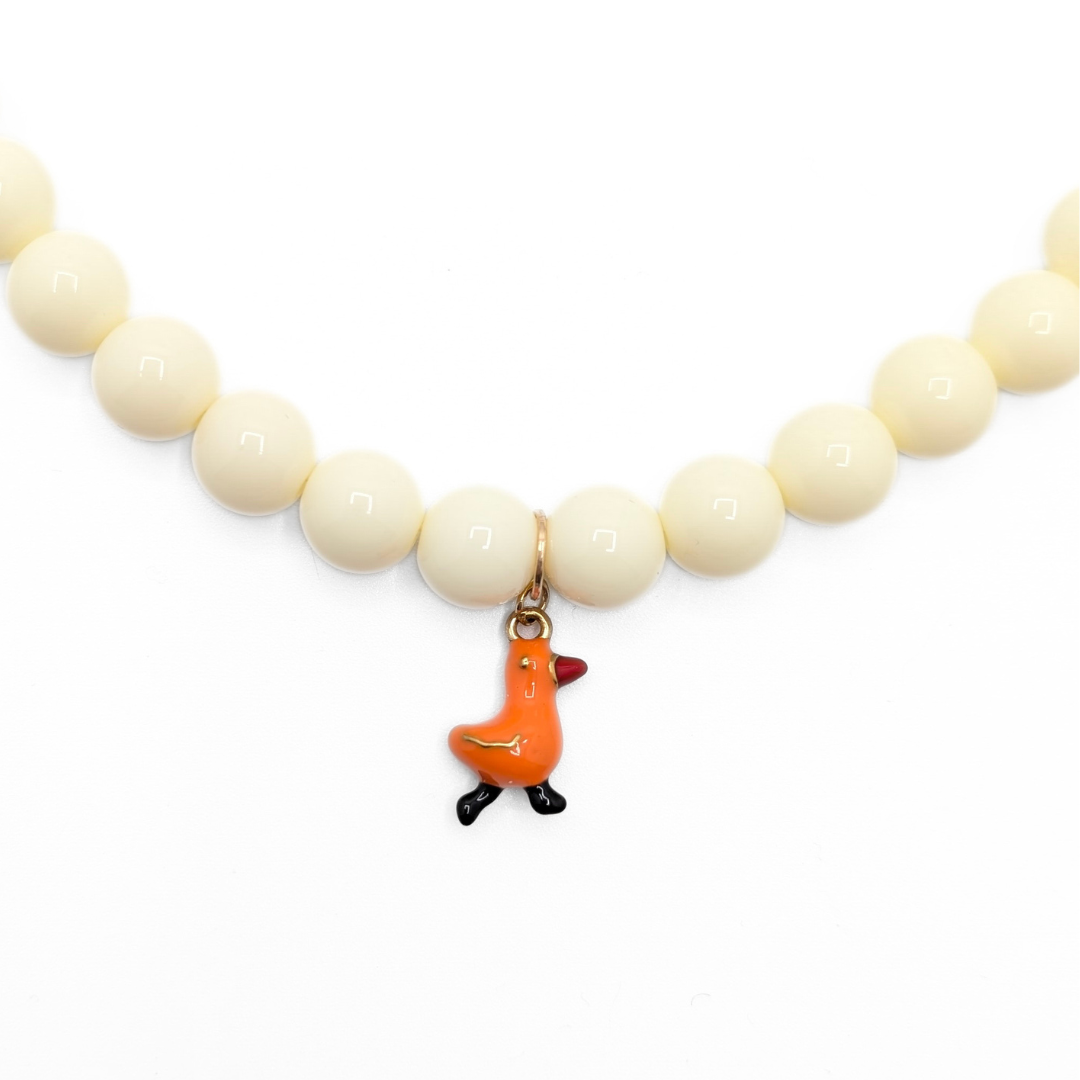 Inzoom crèmekleurige kralenketting met oranje eendje bedel van Casa Jadel