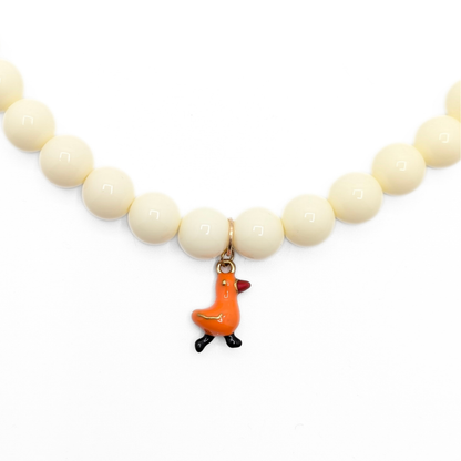Inzoom crèmekleurige kralenketting met oranje eendje bedel van Casa Jadel