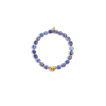 Blauw keramisch armbandje met gestreepte kralen en een goudkleurige hartjes bedel, gefotografeerd op witte achtergrond.