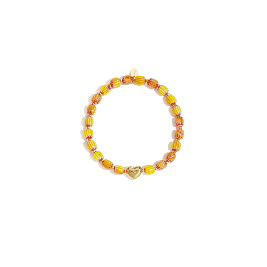 Geel-oranje keramisch armbandje met gestreepte kralen en een goudkleurige hartjes bedel op witte achtergrond.