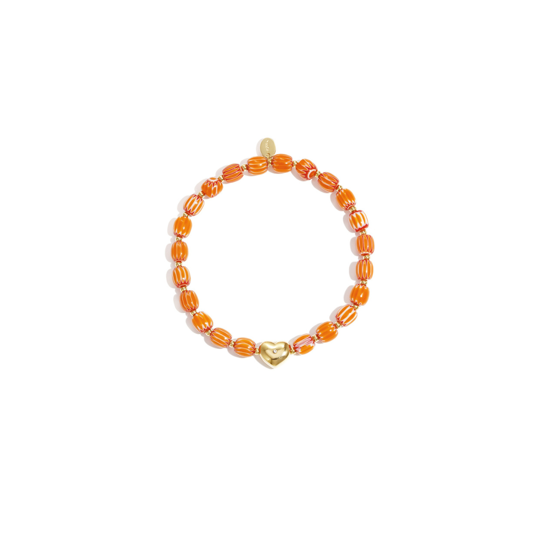 Oranje keramisch armbandje met gestreepte kralen en een goudkleurige hartjes bedel, gefotografeerd op witte achtergrond.