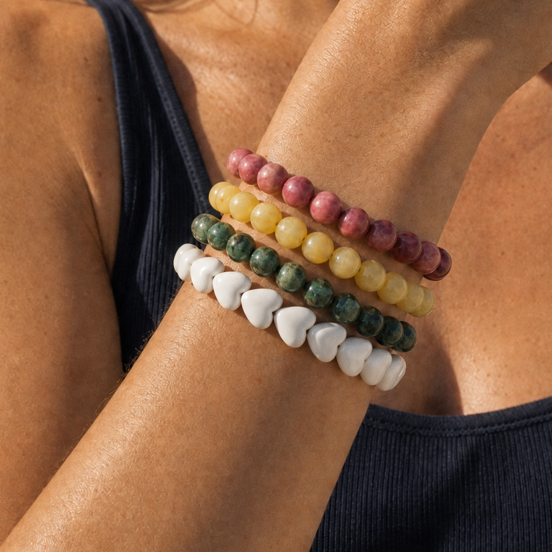 Pols met kleurrijke armbanden stack met roze, gele, groene en witte hartjes armbanden van Casa Jadel
