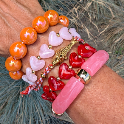 Kleurrijke armbanden stack met oranje kralen, roze hartjes, rode hartjes, roze chunky kralen en gouden vis bedel
