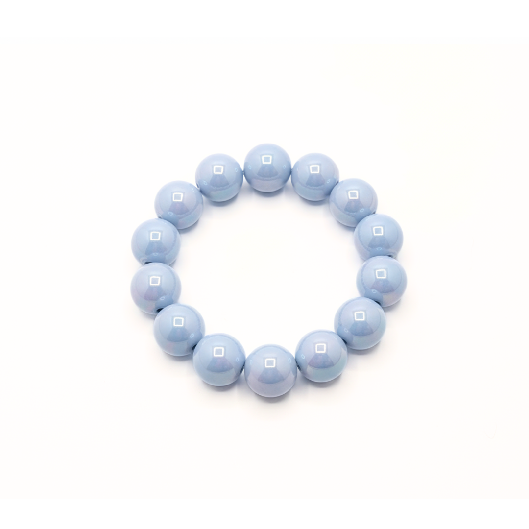 Lichtblauwe chunky kralenarmband met grote glanzende kralen op lichte achtergrond schuin