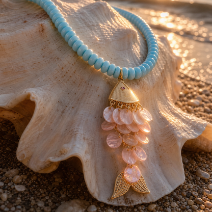Lichtblauwe kralenketting met goudkleurige hanger en roze schelpdetails op grote schelp van Casa Jadel