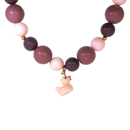 Lichtroze badeendje bedel gedragen aan een kralenketting, zachte en speelse Ibiza-style sieraden van Jadel.