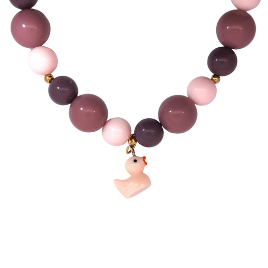 Lichtroze badeendje bedel gedragen aan een kralenketting, zachte en speelse Ibiza-style sieraden van Jadel.