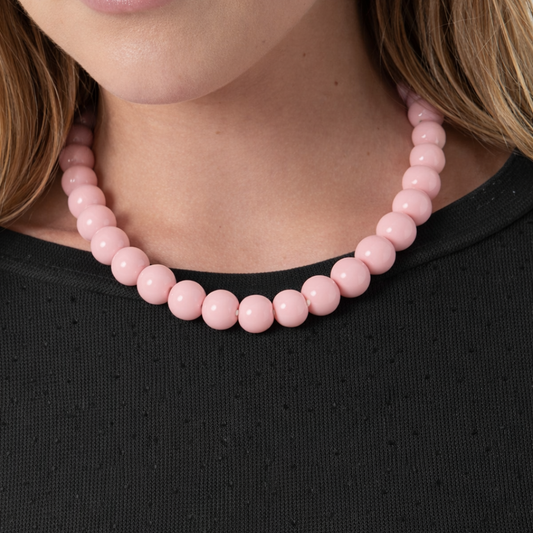 Model draagt lichtroze kralenketting met ronde kralen van Casa Jadel, minimalistische ketting in zachte roze tint