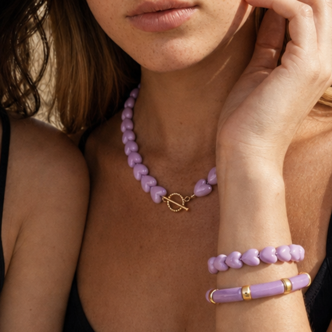 Model draagt een lila hartjesketting met bijpassende lila armbanden van Casa Jadel