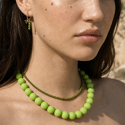 Model draagt een limegroene kralenketting met fijne groene kralenketting en groene oorbel van Casa Jadel
