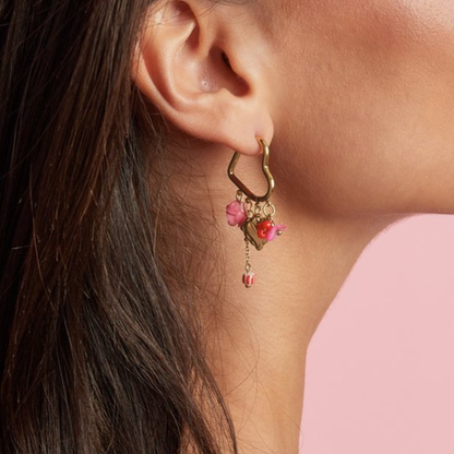 model met Gouden oorbellen met libelle bedel, hartje en pastel kralen.