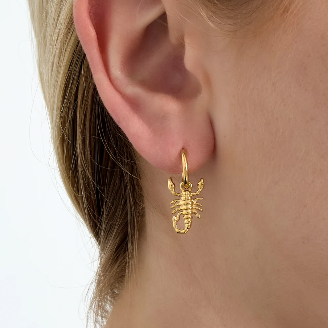 Model met gouden oorbellen met schorpioen | Casa Jadel