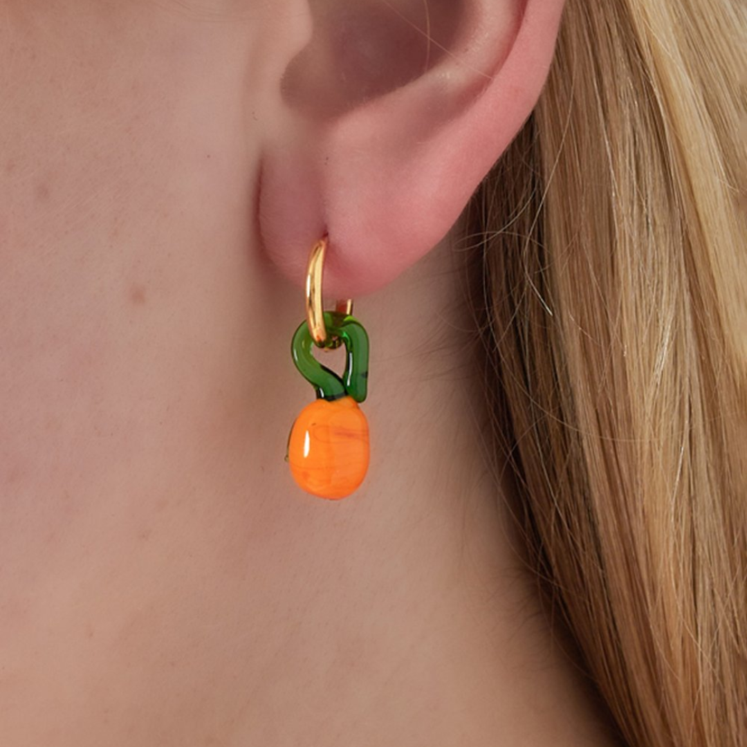 Model met ouden oorbellen met sinaasappel bedel in groen en oranje voor dames.