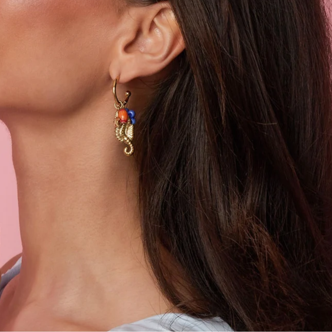 model met gouden oorbellen met zeepaardje, zeester en kleurrijke kralen voor dames.