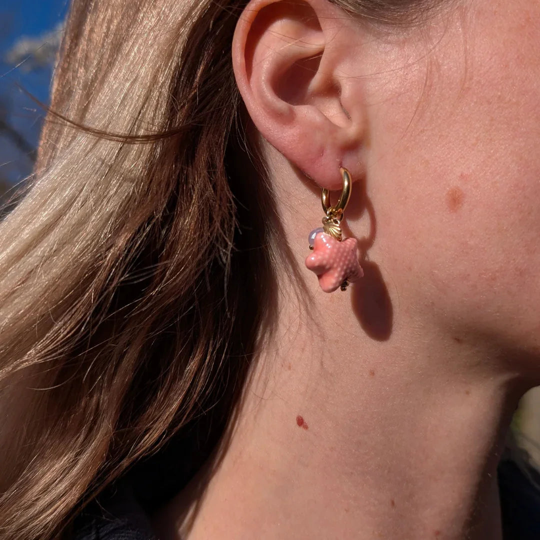 Model met gouden oorringetjes met oranje zeester kraal en schelp - Casa Jadel