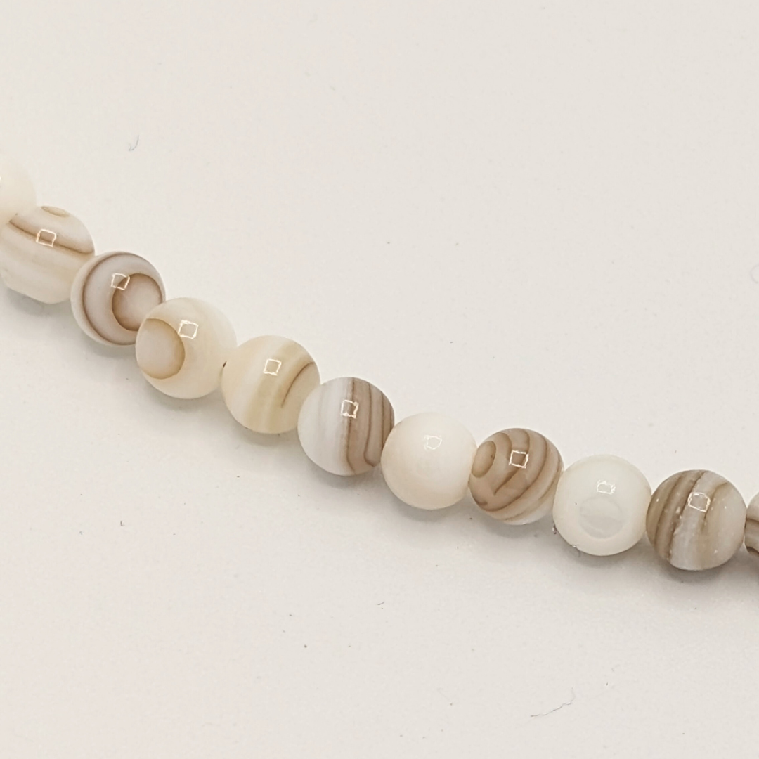 Detail van witte natuurstenen kralenketting met kleine ronde kralen en subtiel gemarmerd patroon