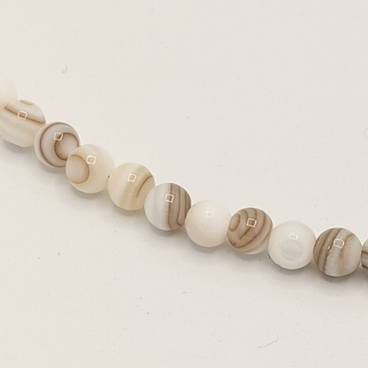 Detail van witte natuurstenen kralenketting met kleine ronde kralen en subtiel gemarmerd patroon