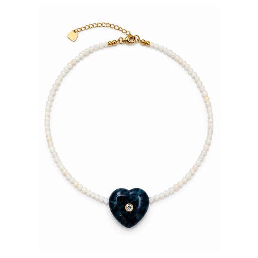 Kleine kralenketting Saar met melkwitte opaal kraaltjes, een diepblauw apatiet hartje met steentje en een goudkleurige sluiting op een witte achtergrond.