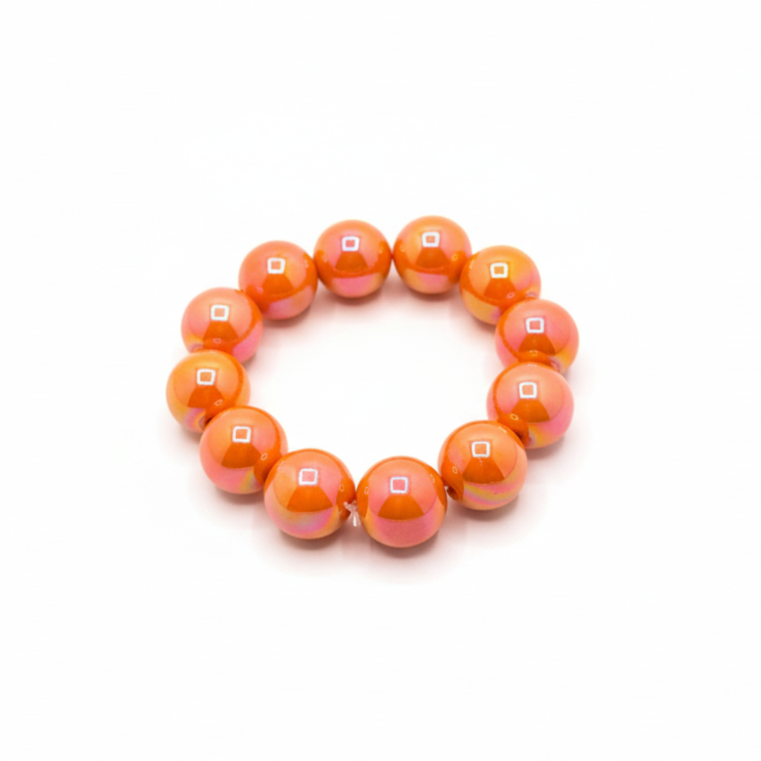 Oranje chunky kralenarmband met grote glanzende kralen op lichte achtergrond schuin.