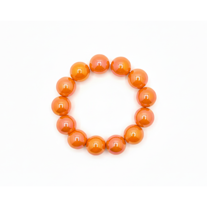 Oranje chunky kralenarmband met grote glanzende kralen op lichte achtergrond.