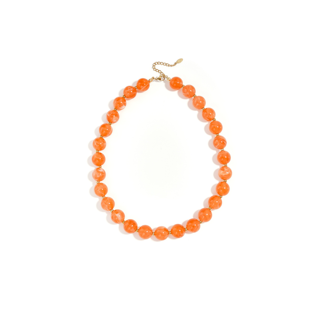Oranje gemarmerde kralenketting met goudkleurige accenten op lichte achtergrond.