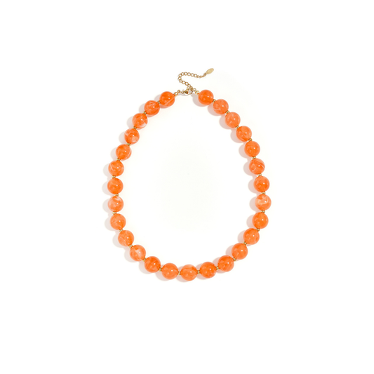 Oranje gemarmerde kralenketting met goudkleurige accenten op lichte achtergrond.