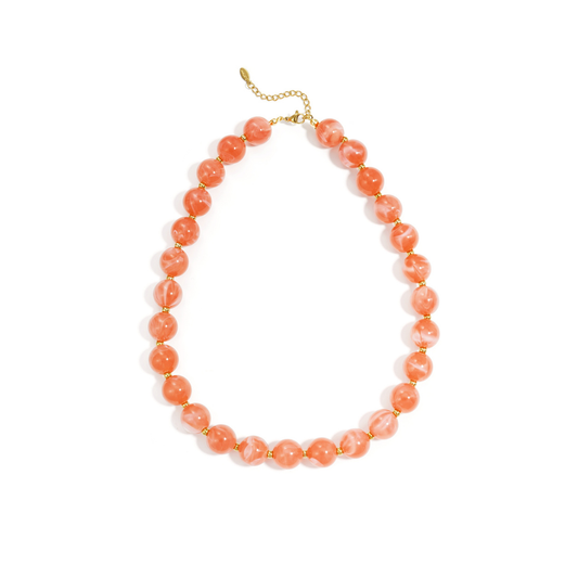 Oranje gemarmerde kralenketting met goudkleurige accenten op lichte achtergrond.