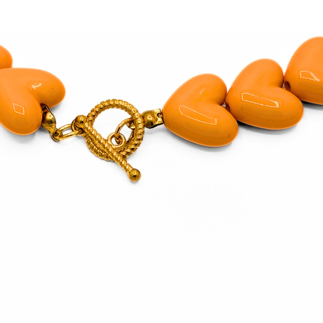 Detail van oranje hartjes kralenketting met gouden toggle frontsluiting Ibiza style sieraden Casa Jadel