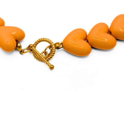 Detail van oranje hartjes kralenketting met gouden toggle frontsluiting Ibiza style sieraden Casa Jadel