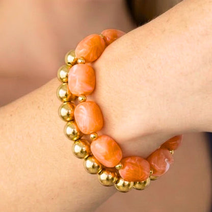 Oranje kralenarmband met goudkleurige kralen gedragen om de pols – zomerse dames armband van Casa Jadel in Ibiza style.