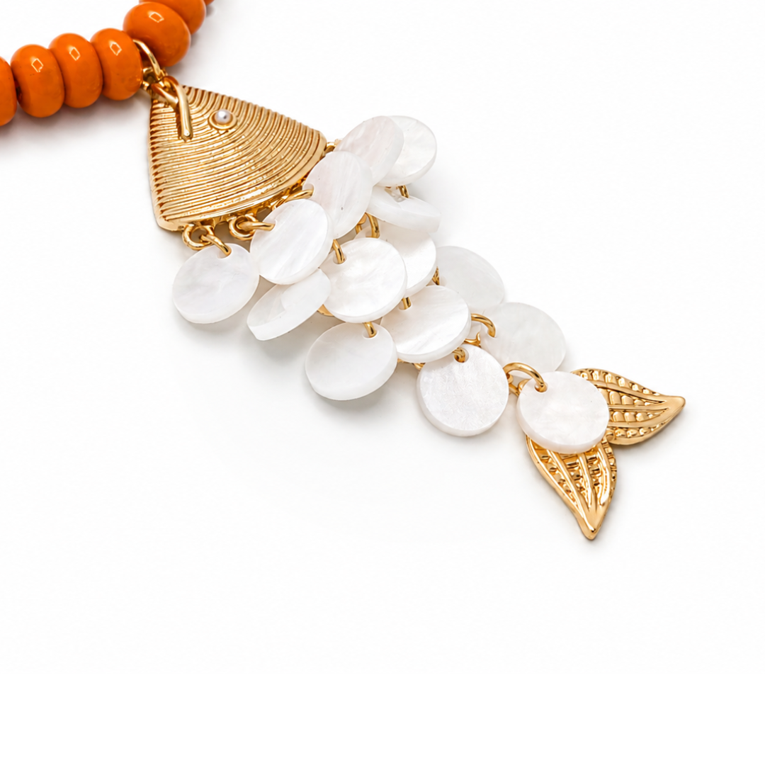 Close up oranje lange kralenketting met gouden vis bedel en schubben van natuurlijke schelp van Casa Jadel.