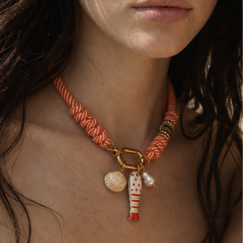 Model draagt oranje rope ketting met vis schelp en parel bedels van Casa Jadel

