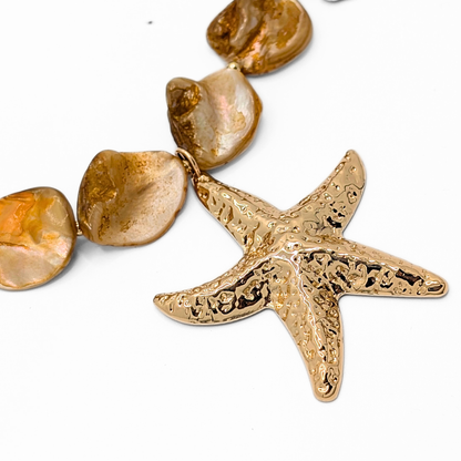 Detail oranje schelpen ketting met gouden zeester bedel