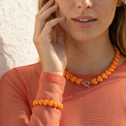 model met oranje shirt en oranje hartjes armband en oranje hartjes ketting