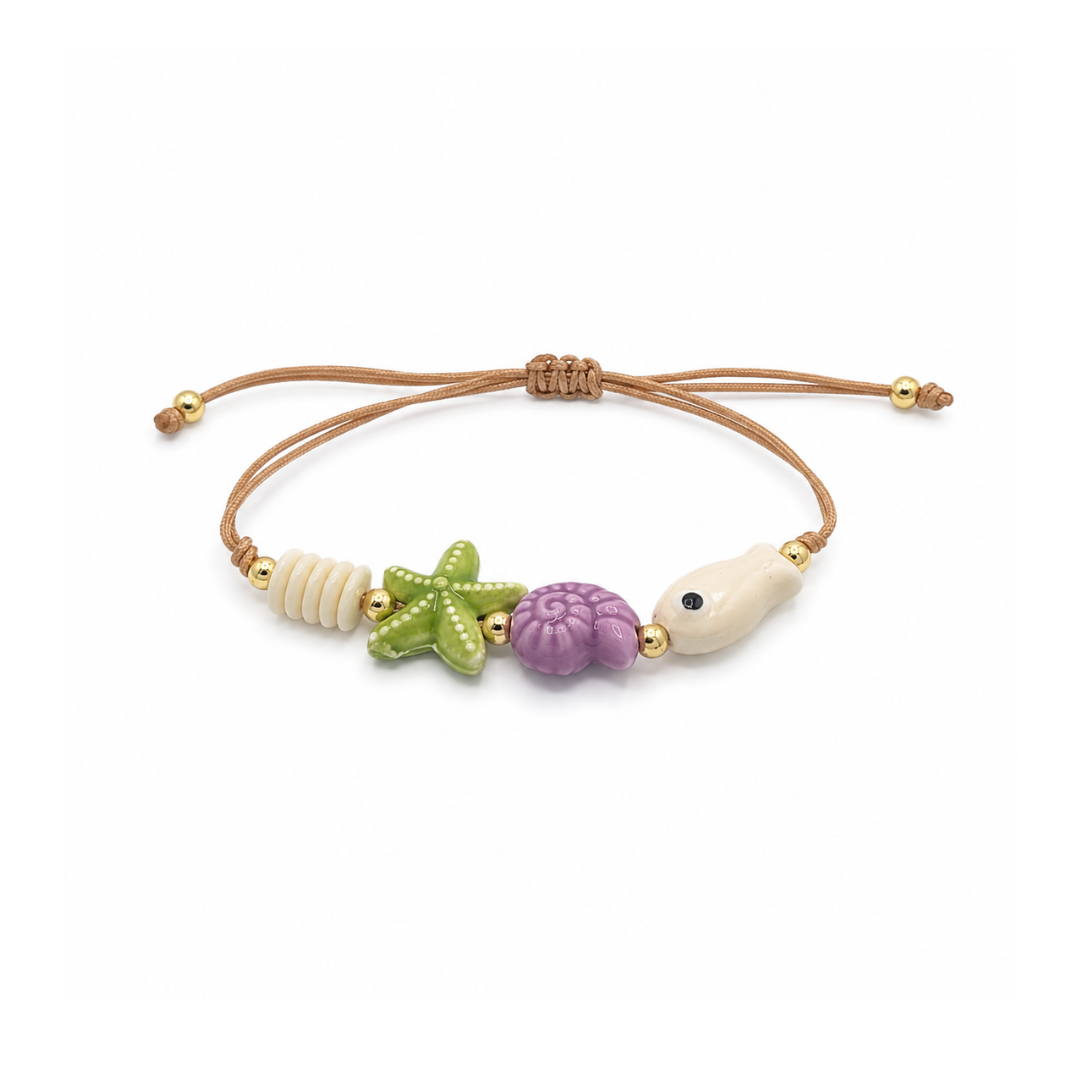 Verstelbaar rope armbandje met groene zeester, paarse schelp, crèmekleurige vis en goudkleurige details.