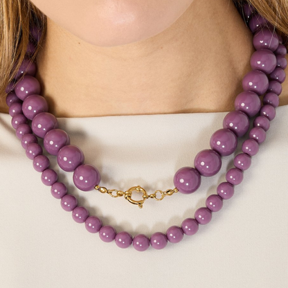Detail van paarse kralenketting gedragen om de hals met ronde kralen