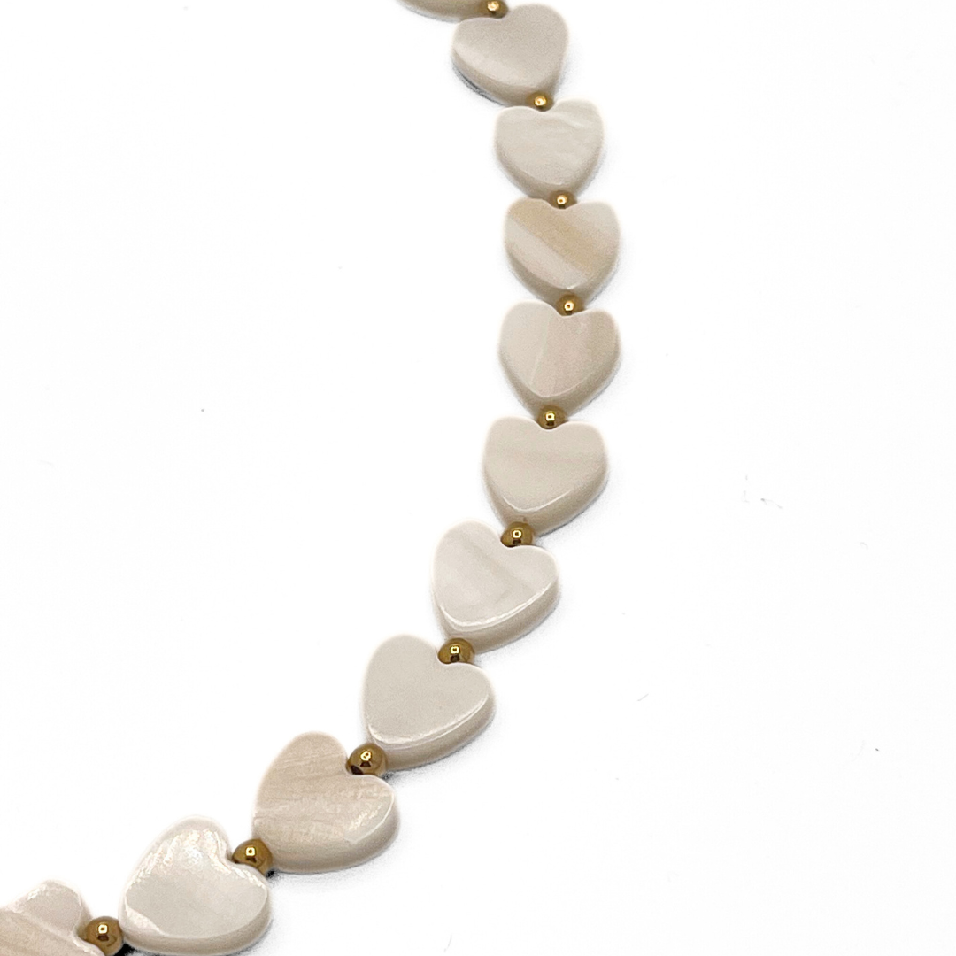Detail van parelmoer hartjes kralenketting met kleine gouden kralen en zachte glans