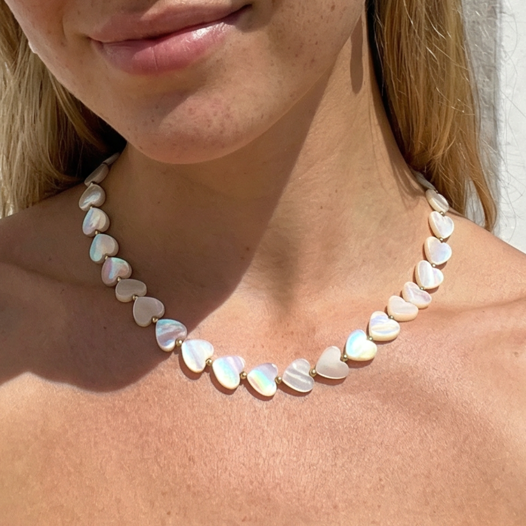 Parelmoer hartjes kralenketting gedragen door model subtiele luxe zomerse sieraden trend