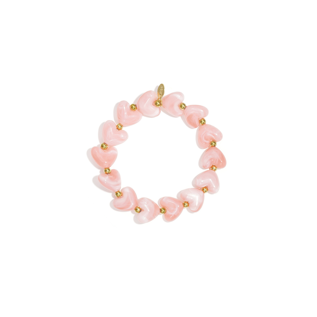 Peach hartjes kralenarmband met glanzende marmerlook kralen en goudkleurige details op witte achtergrond.