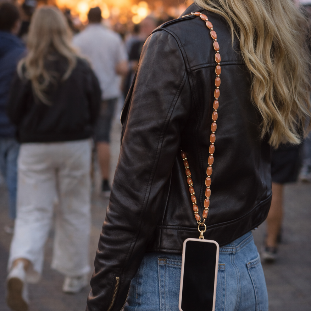 model met Perzikroze chunky telefoonkoord met langwerpige kralen en goudkleurige sluiting.