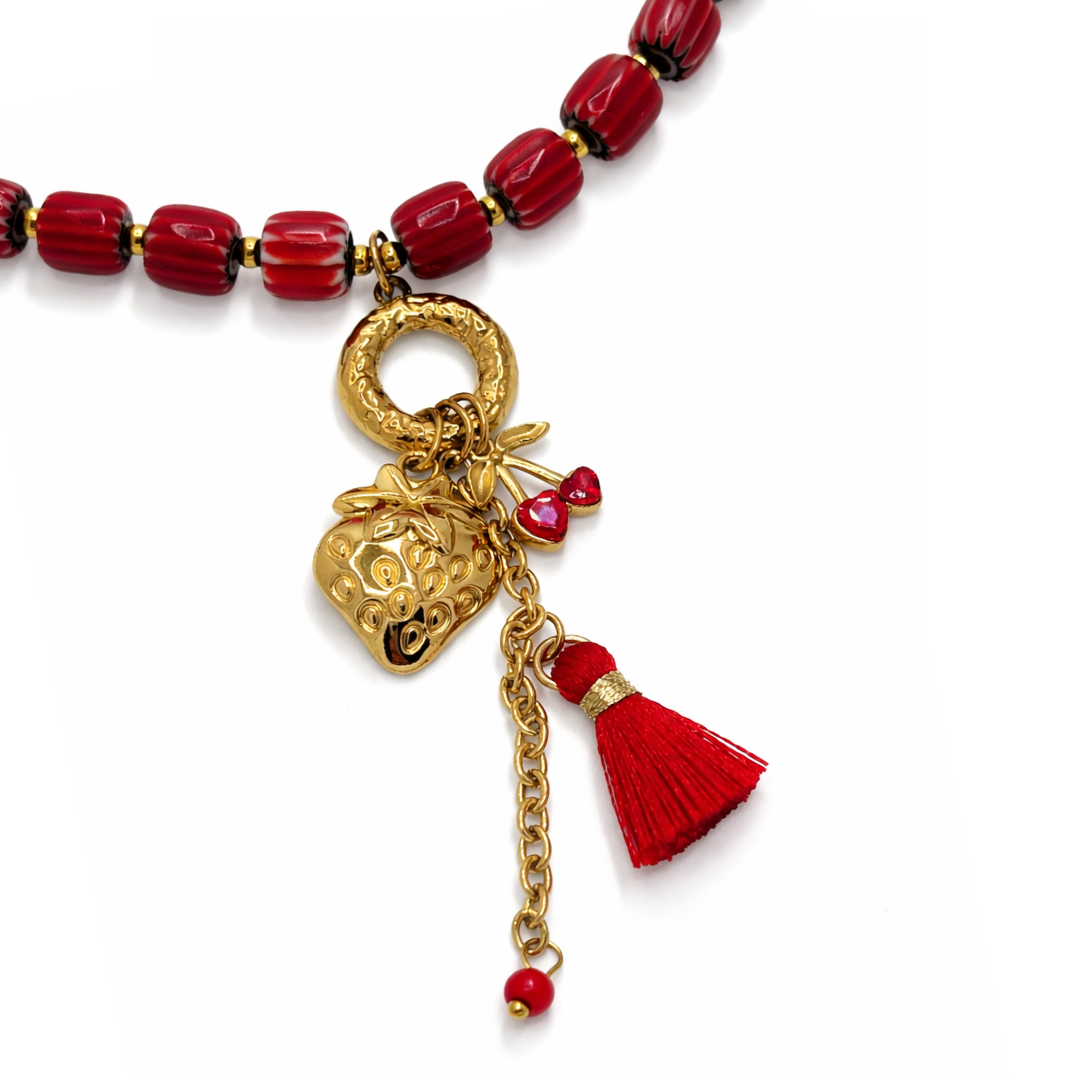 Inzoom rode glazen kralenketting dames met gouden aardbei bedel en rood kwastje Ibiza stijl