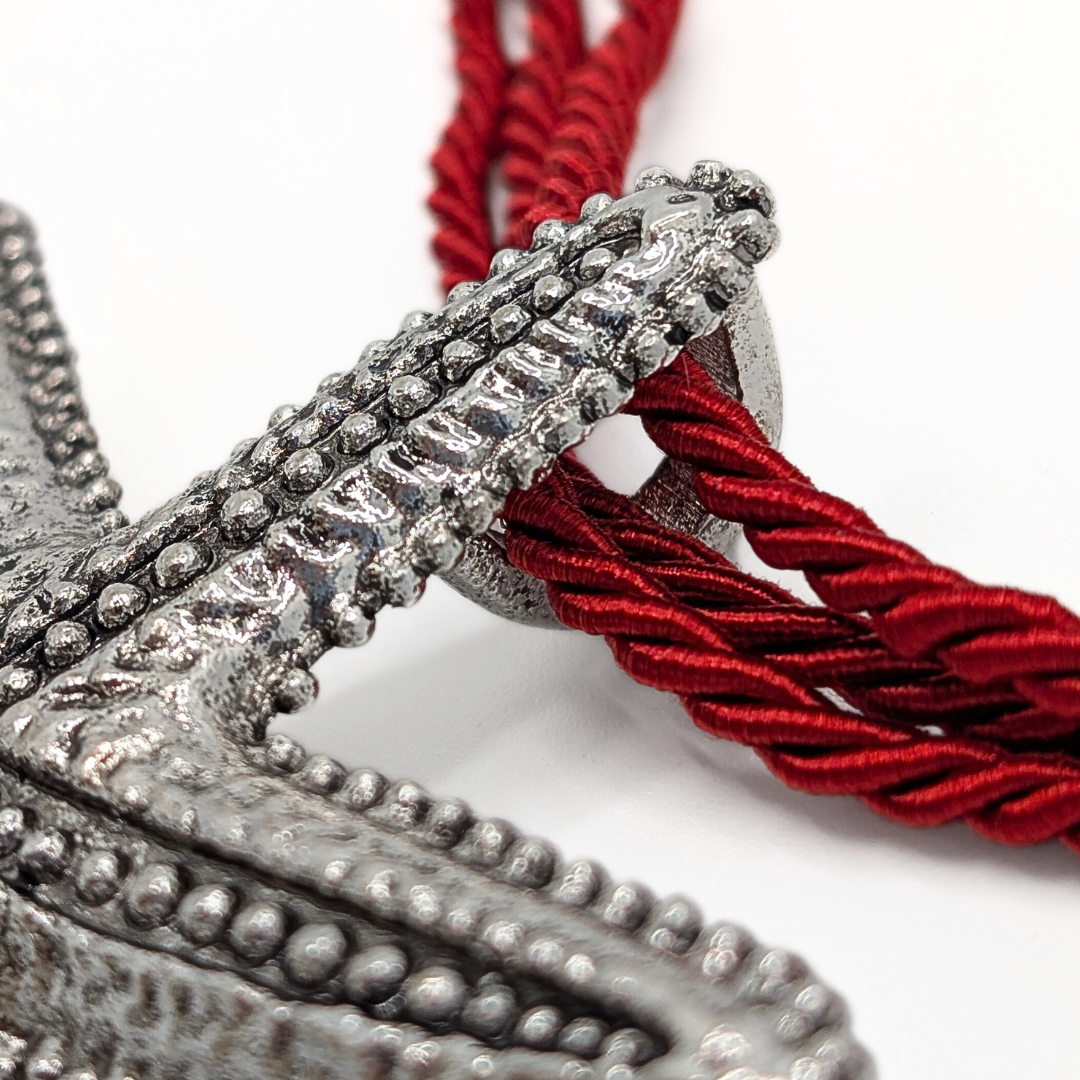 Detail van zilveren zeester hanger bevestigd aan rode rope ketting