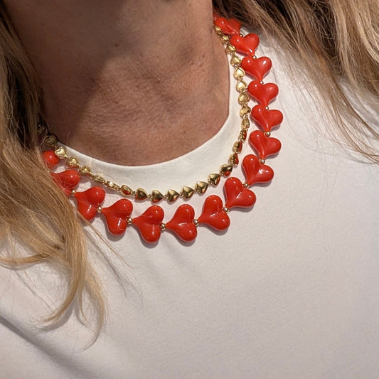 rode hartjes ketting met gouden detail en gouden hartjes ketting op wit tshirt