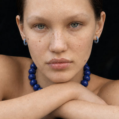 Model draagt een royalblauwe kralenketting met blauwe oorringen van Casa Jadel