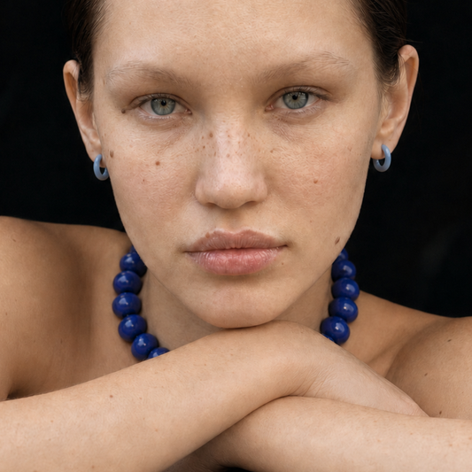 Model draagt een royalblauwe kralenketting met blauwe oorringen van Casa Jadel