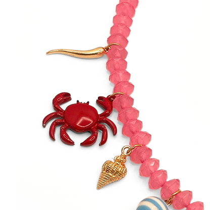 Detail roze kralenketting met grote zon bedel en strand bedels