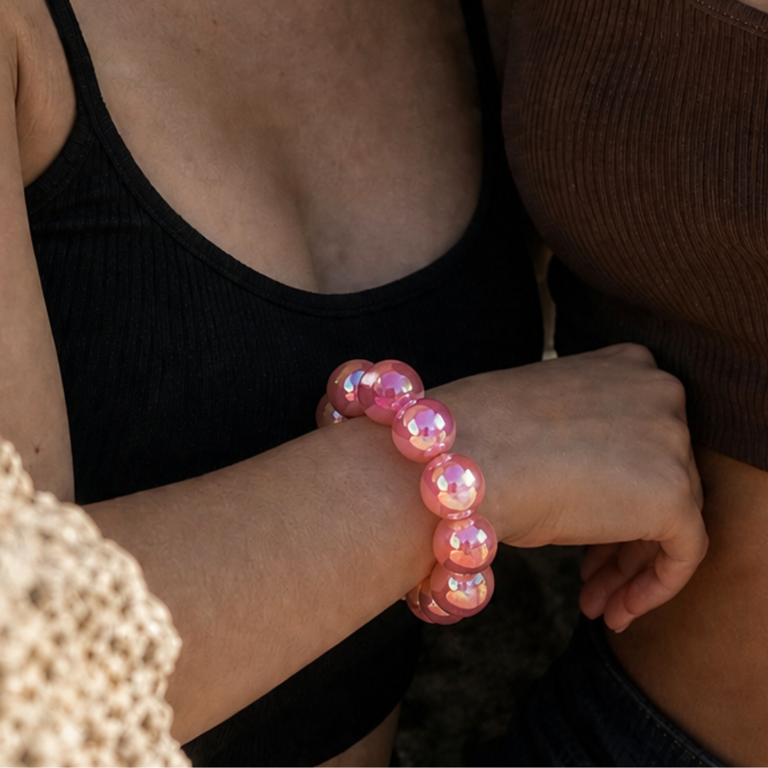 Pols met roze glanzende kralenarmband met iriserende kralen van Casa Jadel