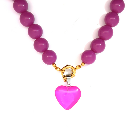 Roze hartje bedel gedragen aan donkerroze kralenketting met boei slotje