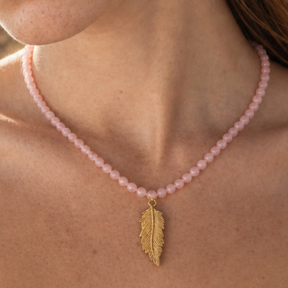 Model draagt roze kralenketting met gouden veer bedel van Casa Jadel