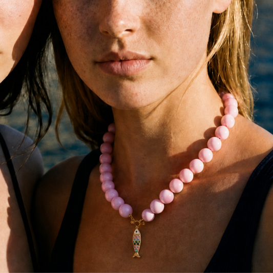 Model draagt roze kralenketting met kleurrijke vis bedel van Casa Jadel
